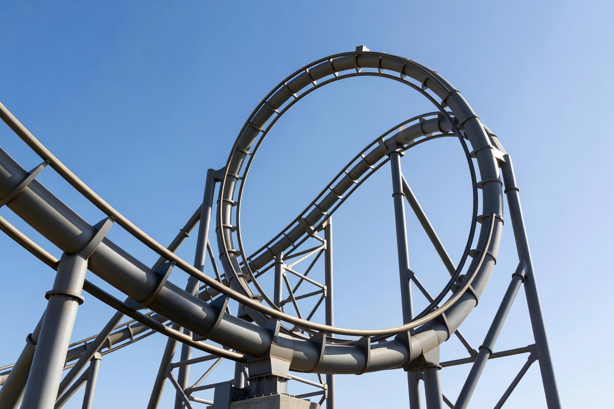 Close view of a steel coaster track twisting into a zero-gravity roll against the sky